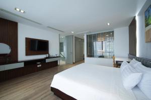 Un dormitorio con una cama blanca y un televisor. en Villa Nha Trang View Biển - View City, en Nha Trang