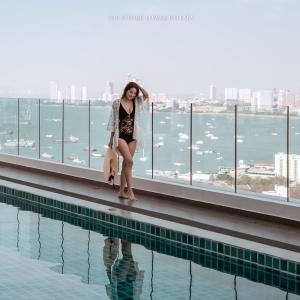 uma mulher à beira de uma piscina em Sea View 2 Bed Room Rare Beauty em Praia de Jomtien