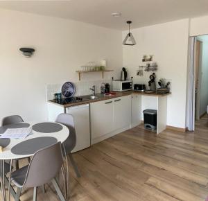 Una cocina con gabinetes blancos y una mesa y sillas. en Villa del Re 2 face à la piscine, en La Flotte