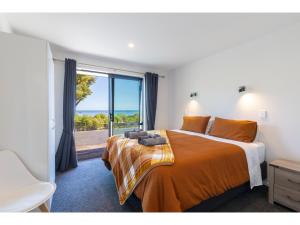 a bedroom with a bed with a view of the ocean at Glass Horizon - Rutherglen Holiday Home in Greymouth
