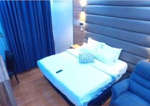 a bedroom with a white bed and a blue chair at Grand Diamond Hotels & Suites LTD in Owerri