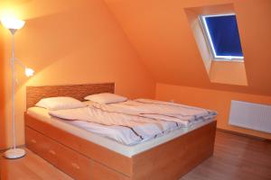 ein Schlafzimmer mit einem Bett mit orangefarbener Decke in der Unterkunft Penzion Veritas in Vranovice