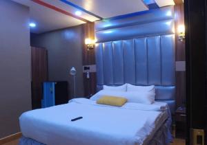 a bedroom with a large white bed with a blue headboard at Grand Diamond Hotels & Suites LTD in Owerri