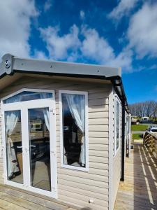 a small shed with windows on a deck at The Canny View at Three Lochs Holiday Park in Balminnoch 3 bedroom sleeps upto 8 guests in Newton Stewart