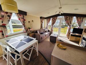 a living room with a table and a couch at The Canny View at Three Lochs Holiday Park in Balminnoch 3 bedroom sleeps upto 8 guests in Newton Stewart