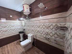 a bathroom with a toilet in a room with wooden walls at Noorani Hills Home Stay 2 BHK in Patta