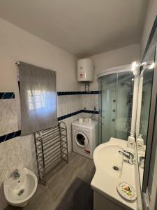 a bathroom with a sink and a washing machine at Appartamento Zafferano in LʼOpaco