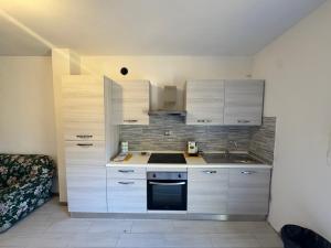a kitchen with white cabinets and a stove top oven at Appartamento Zafferano in LʼOpaco