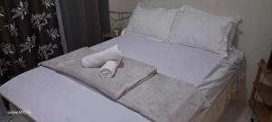 Una cama blanca con toallas y almohadas. en Sandstone Unit Brenthill Condo, en Baguio