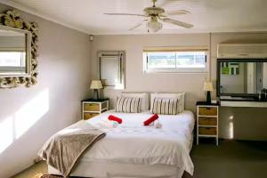 a bedroom with a large white bed with red pillows at 90 On Wellington Cottage in Port Elizabeth