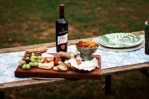 a bottle of wine and a plate of food on a table at 90 On Wellington Cottage in Port Elizabeth
