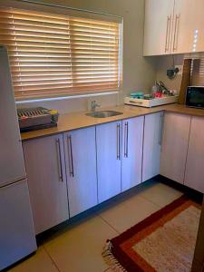 a kitchen with white cabinets and a sink at 90 On Wellington Cottage in Port Elizabeth +15 photos