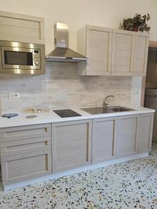 a kitchen with white cabinets and a sink and a microwave at La casa di Maria in Lipari