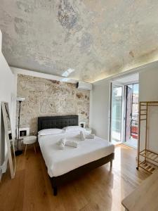 Un dormitorio con una gran cama blanca y una pared de piedra. en Valverde Home, en Palermo
