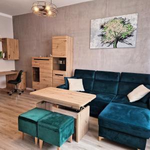 Una sala de estar con un sofá azul y una mesa. en Apartament Królewiecka 54b/26, en Mrągowo