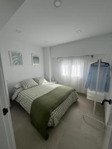 a white bedroom with a bed and a window at Apartamento La Placeta in Alameda