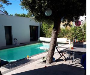 ein Baum und ein Stuhl neben einem Swimmingpool in der Unterkunft Kaze Océane in Brétignolles-sur-Mer