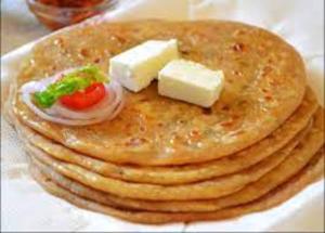 una pila de panqueques con queso y tomates encima en Melody Orchard Cottage, en Jagatsukh