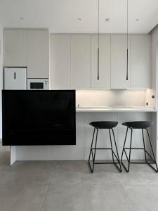 a kitchen with white cabinets and a counter with two stools at Zero Point Nafpaktos in Nafpaktos +20 photos