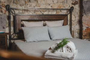 ein Bett mit weißen Kissen und eine Steinwand in der Unterkunft Moinho do Ourives in Friumes