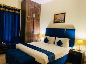 a bedroom with a large bed and blue curtains at Infinity Hotel in Lahore +46 photos