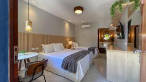 a hotel room with a bed and a table and a desk at Charme da Vila Suítes in Porto De Galinhas +62 photos