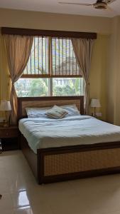 a bed in a bedroom with a large window at Seneh Homes Cultural Stay 2BHK Dispur in Guwahati