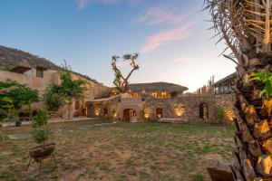 Sunanda by 1810AD - A Boutique Organic Retreat في بوشكار: منظر خارجي لبيت حجري مع ساحة