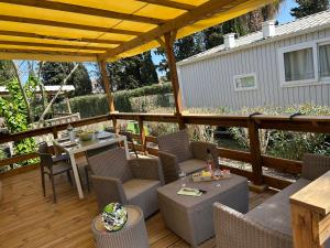 a patio with a table and chairs on a deck at Mobile home sirène luxe Camping le Bosc 4 étoiles 3 chambres in Saint-Cyprien