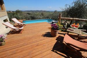 a wooden deck with chairs and a swimming pool at Happy Tuscany in Rigomagno
