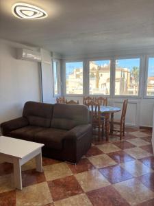 Una sala de estar con un sofá, una mesa y sillas. en Apartamento Torcasol, en Torrox Costa