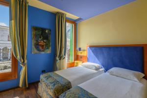 a blue bedroom with two beds and a window at Diamantino Town House in Padova