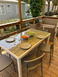 a table and chairs on a deck with food on it at Mobile home sirène luxe Camping le Bosc 4 étoiles 3 chambres in Saint-Cyprien