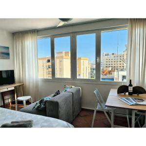 ein Wohnzimmer mit einer Couch und einem Tisch und Fenstern in der Unterkunft Helios II - Free Parking - By Lcdsol in Torremolinos