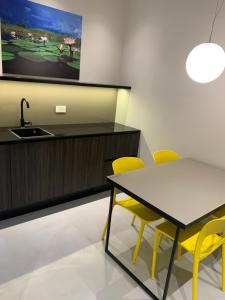 a kitchen with a sink and a table and yellow chairs at Donna Caterina in Monopoli