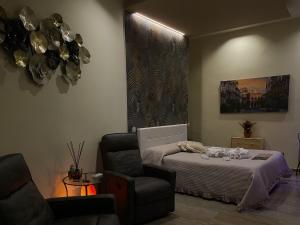 a bedroom with a bed and a chair and a chandelier at Pittà Room Suite & Private SPA in Catania