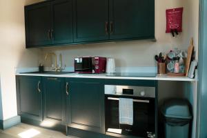 a kitchen with green cabinets and a microwave at The Snook-Free Parking-Near Pentland Hills in Loanhead