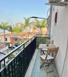 un balcone con tavolo e sedia in legno su un edificio di Scalinata del Nespolo Acitrezza ad Acitrezza
