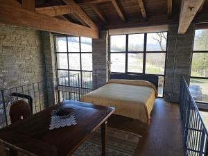 a bedroom with a bed and a table and windows at Sogni nel Bosco in Varsi