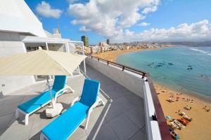 Un balcón con dos sillas azules y una playa. en Apartamentos Juan Pérez- Viviendas Vacacionales, en Las Palmas de Gran Canaria