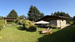 a yard with two lounge chairs and an umbrella at Villa - VALL DI VALL in Pirin Golf & Country Club in Razlog