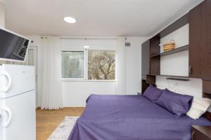 a bedroom with a purple bed and a refrigerator at Apartments Oliva in Utjeha