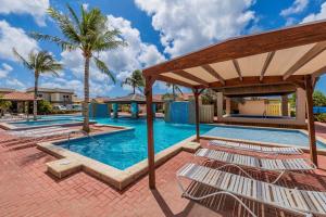 a pool with lounge chairs and palm trees at Treasures at the Pearl Eagle Beach in Palm-Eagle Beach