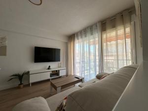 een woonkamer met een bank en een groot raam bij SATORI Romantyczny azyl dla dwojga 150 m od plaży - apartament z balkonem i parkingiem, Playa de Gandia in Playa de Gandia