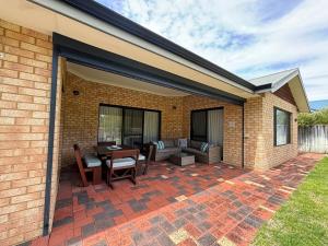 a patio with a table and chairs on a brick wall at Troon Retreat! Golf, Wineries, beaches in Dunsborough