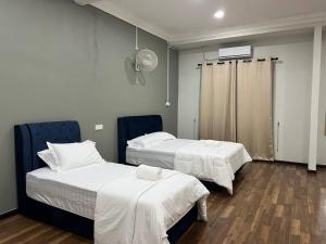 two beds in a hospital room with white sheets at H-One Hotel in Pasir Puteh