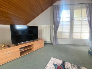a living room with a flat screen tv on a wooden entertainment center at Ferienwohnung Vogelsang in Undeloh