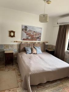 a bedroom with a bed and a picture on the wall at Casa Esperança - carefree living with big private pool and great views in Olhão