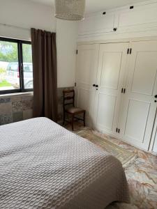 a bedroom with a bed and a chair and a window at Casa Esperança - carefree living with big private pool and great views in Olhão