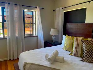 a bedroom with a large bed and two windows at Mount Road Suites in Port Elizabeth